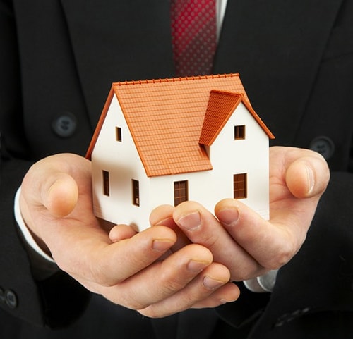 a person holding a model house in their hands